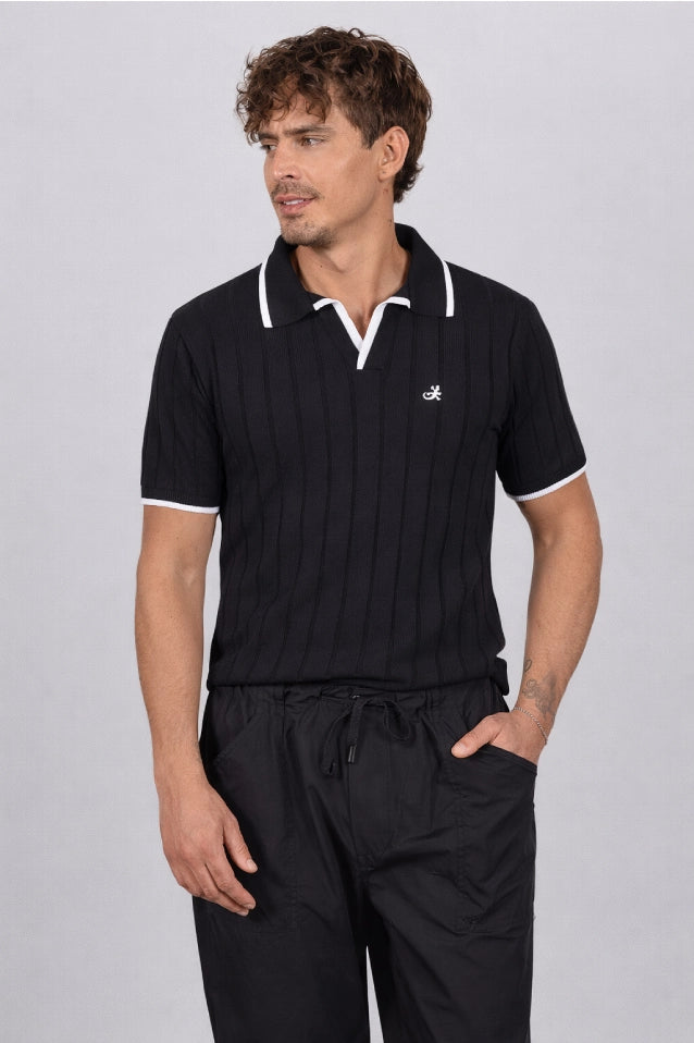 Hombre de 50 años vistiendo la Camisa Afar de LSJ SAS, una prenda tipo polo tejida en algodón 100% sostenible disponible en color negro.