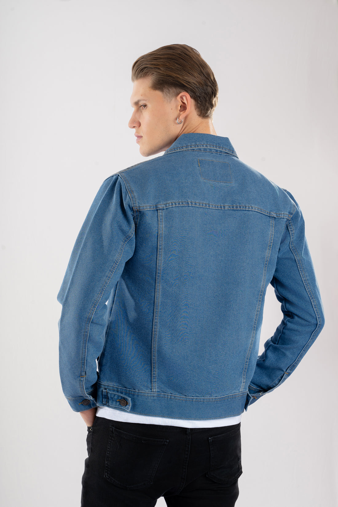 Vista trasera de la chaqueta de jean azul medio para hombre, mostrando el corte clásico y las correas de ajuste en la cintura.