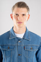 Vista frontal de la chaqueta de jean azul medio para hombre, mostrando el corte clásico y cuello.