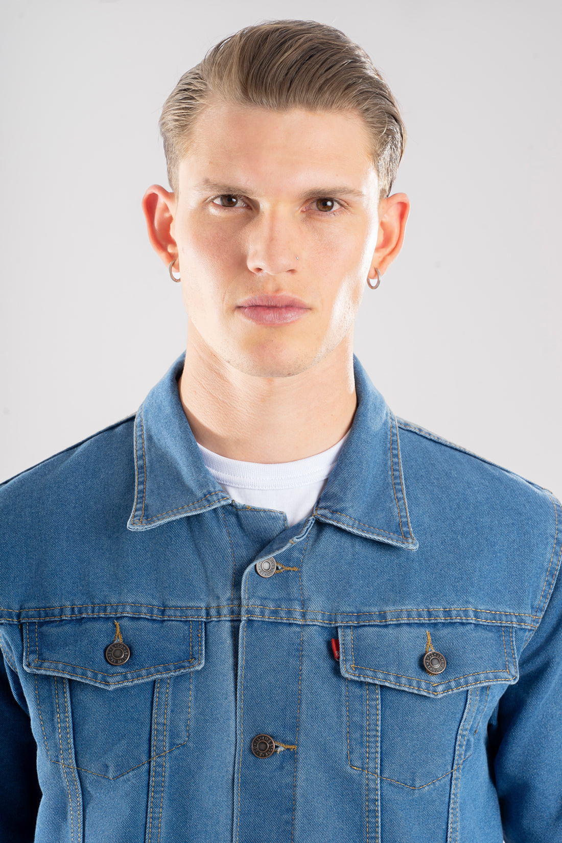 Vista frontal de la chaqueta de jean azul medio para hombre, mostrando el corte clásico y cuello.