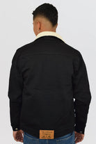 Vista trasera de la chaqueta de jean negra para hombre, mostrando el corte de la espalda y el cuello de ovejero.