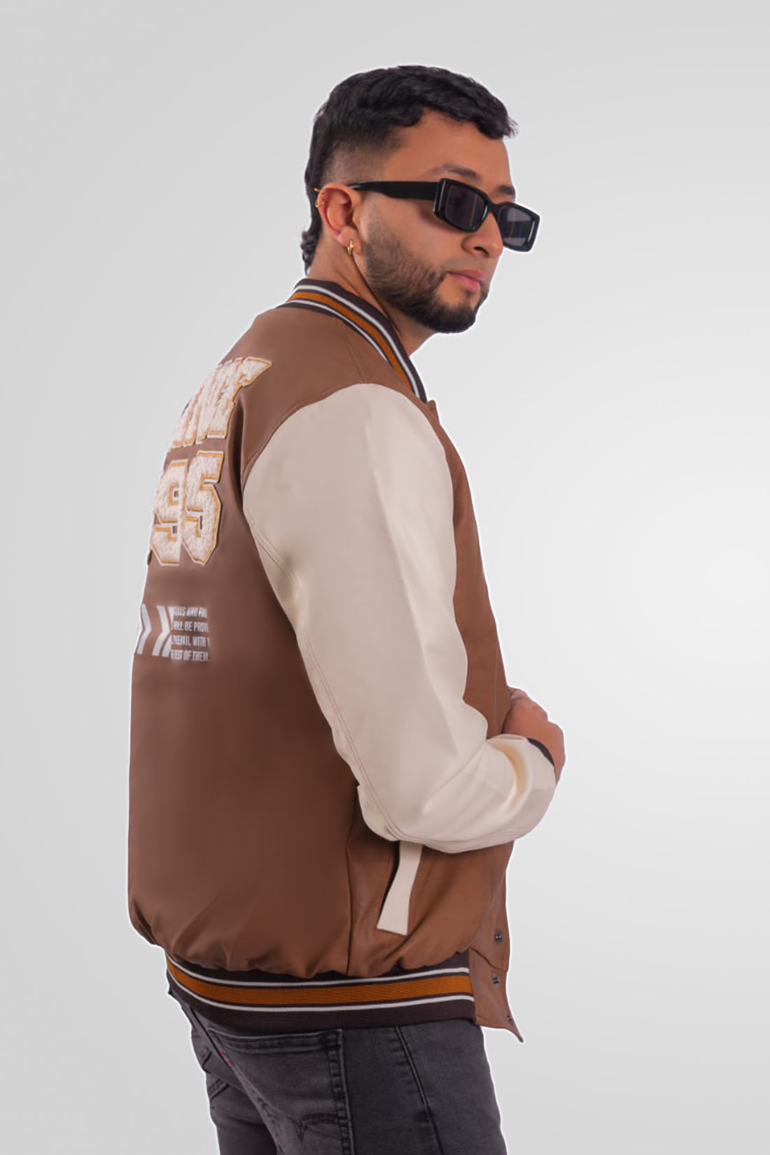 Chaqueta Bomber beisbolera para hombre vista lateral en color cafe claro con logos bordados y material Cuerotex resistente. Disponible con Pago Contra Entrega, crédito ADDI y Sistecrédito en lsjsas.com