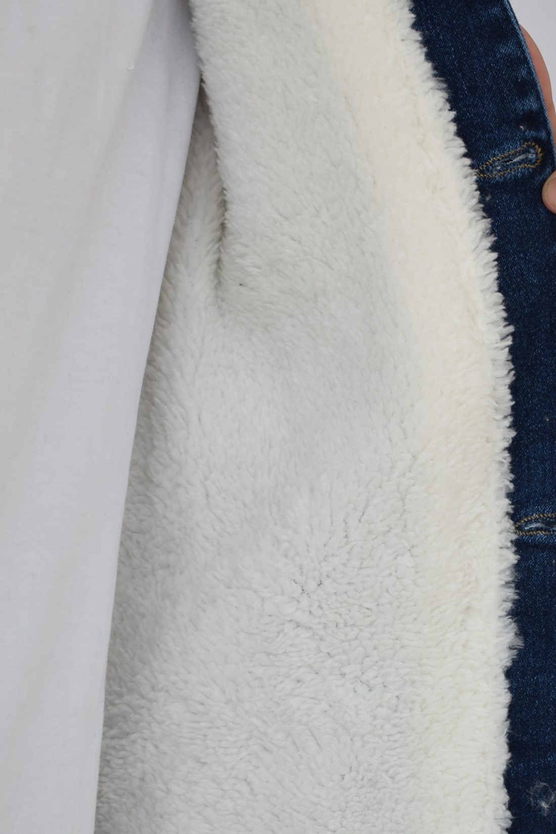 Primer plano de la textura del forro de ovejero blanco y el cuello de una chaqueta de jean azul industrial de hombre.