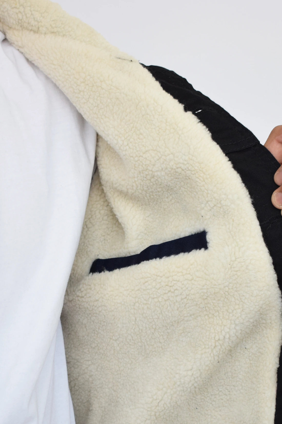 Primer plano de la textura del forro de ovejero blanco y el cuello de una chaqueta de jean negra de hombre.