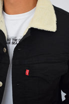 Primer plano de la textura del frente y el cuello de una chaqueta de jean negra de hombre.