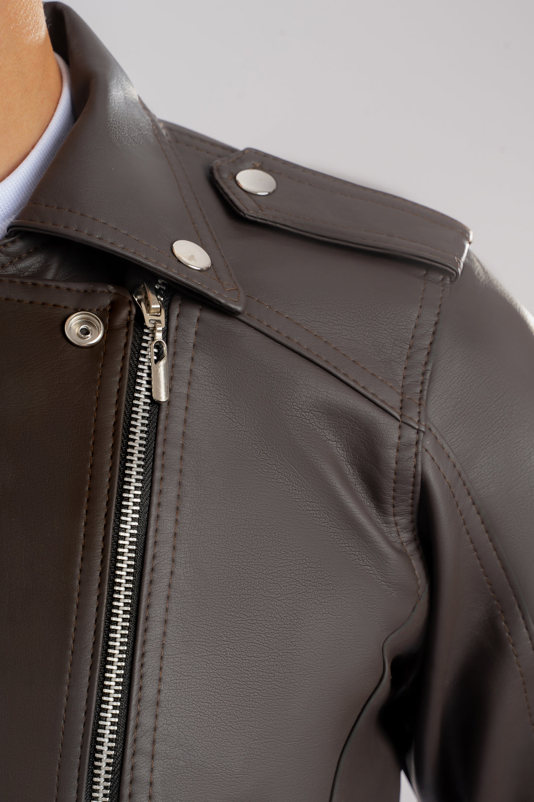 Primer plano hombro de la Chamarra de cuerotex para hombre en color cafe, estilo rebelde con broche, vista frontal.