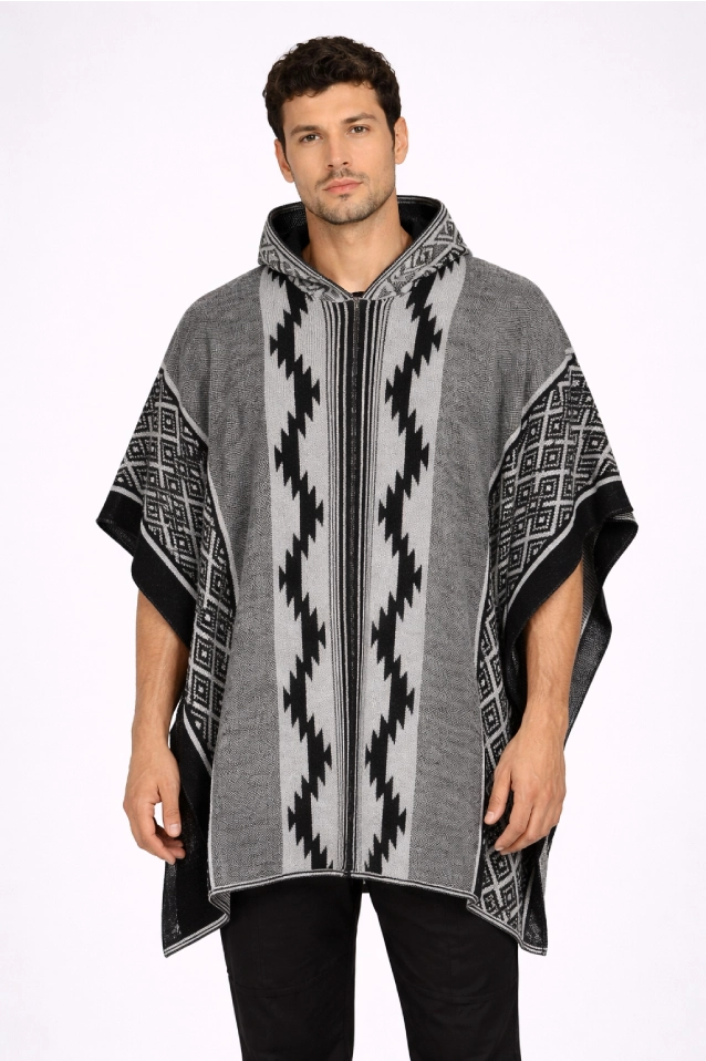 Hombre vistiendo una ruana gris modelo Durango en vista frontal, con capucha, flecos y patrones geométricos (grecas) tejidos.