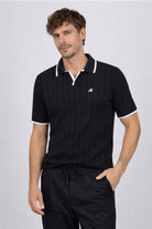 Hombre vistiendo la Camisa Afar de LSJ SAS, una prenda tipo polo tejida en algodón 100% sostenible disponible en color negro.