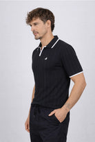 Hombre vistiendo la Camisa Afar vista lateral de LSJ SAS, una prenda tipo polo tejida en algodón 100% sostenible disponible en color negro.