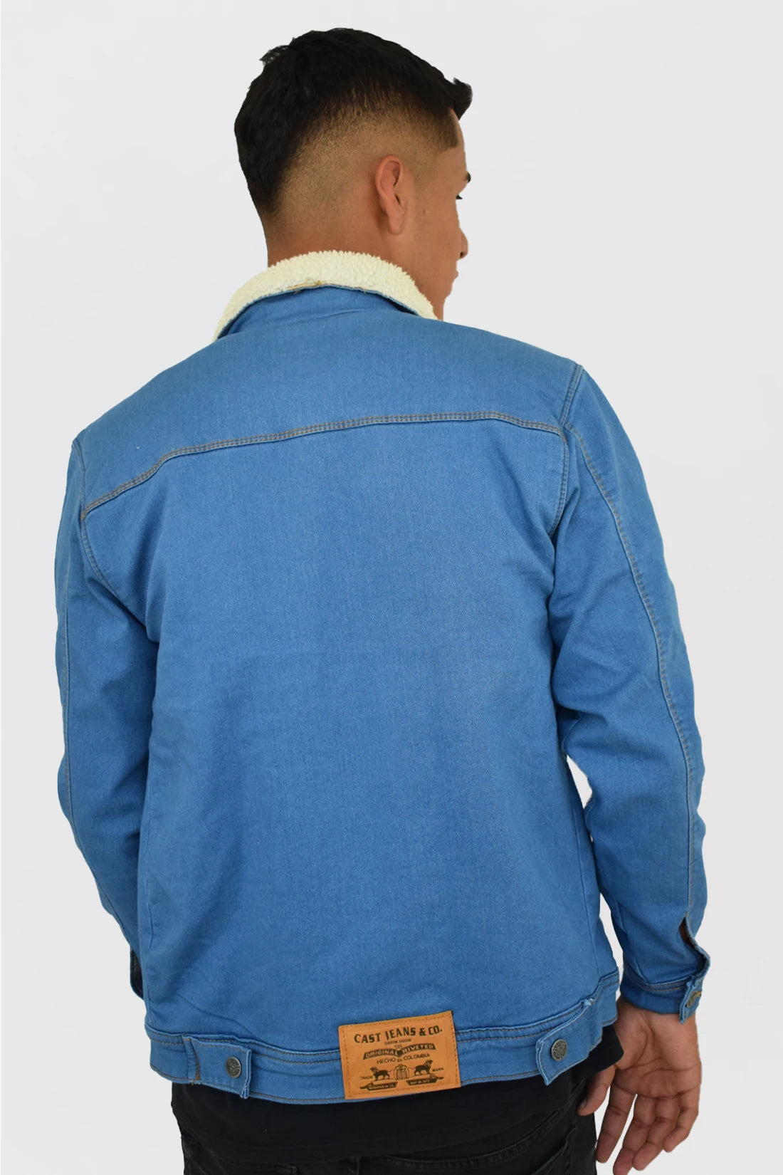 Vista trasera de la chaqueta de jean azul medio para hombre, mostrando el corte de la espalda y el cuello de ovejero.