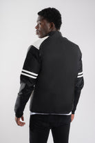 Vista posterior de chaqueta beisbolera negra blanca resaltando el corte y la calidad de confección nacional.