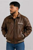 Chaqueta beisbolera oversize café cerrada, con bolsillos ribeteados en cinta rayada crema