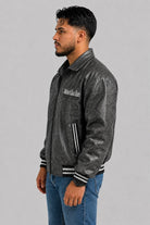 Vista lateral de la chaqueta beisbolera oversize gris oscuro en cuero sintético con hombro caído