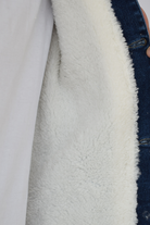 Primer plano de la textura del forro de ovejero blanco y el cuello de una chaqueta de jean azul industrial de hombre.