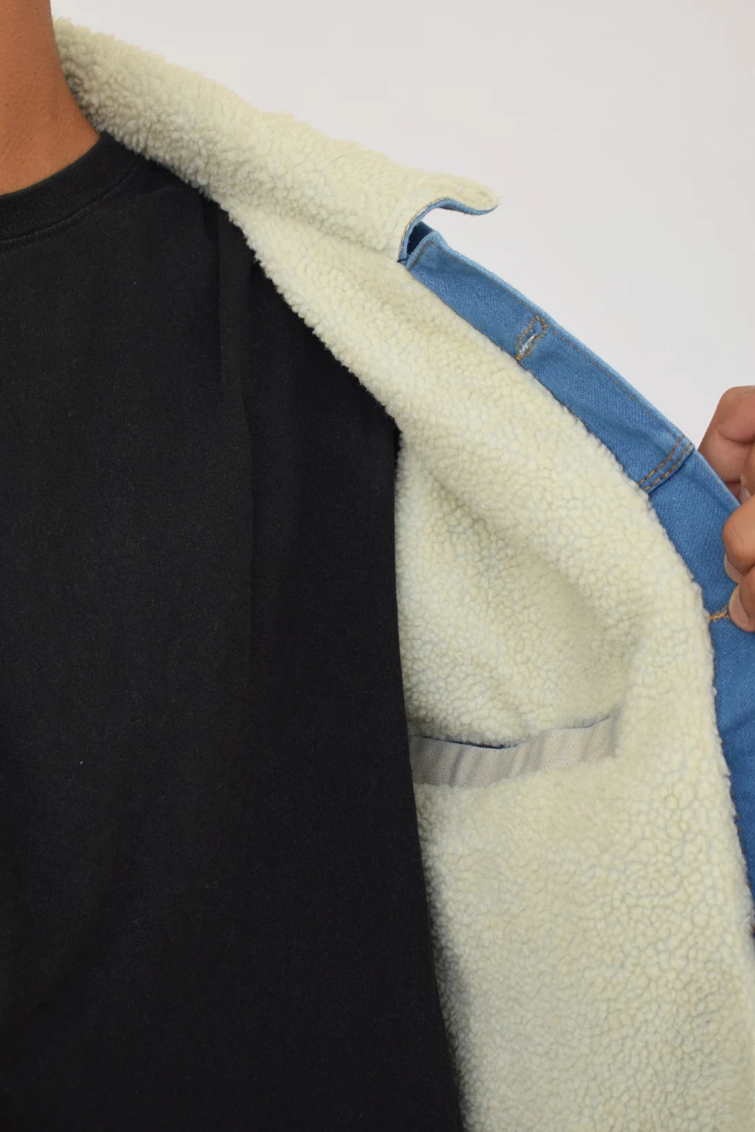 Primer plano de la textura del forro de ovejero blanco y el cuello de una chaqueta de jean azul medio de hombre.