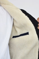 Primer plano de la textura del forro de ovejero blanco y el cuello de una chaqueta de jean negra de hombre.