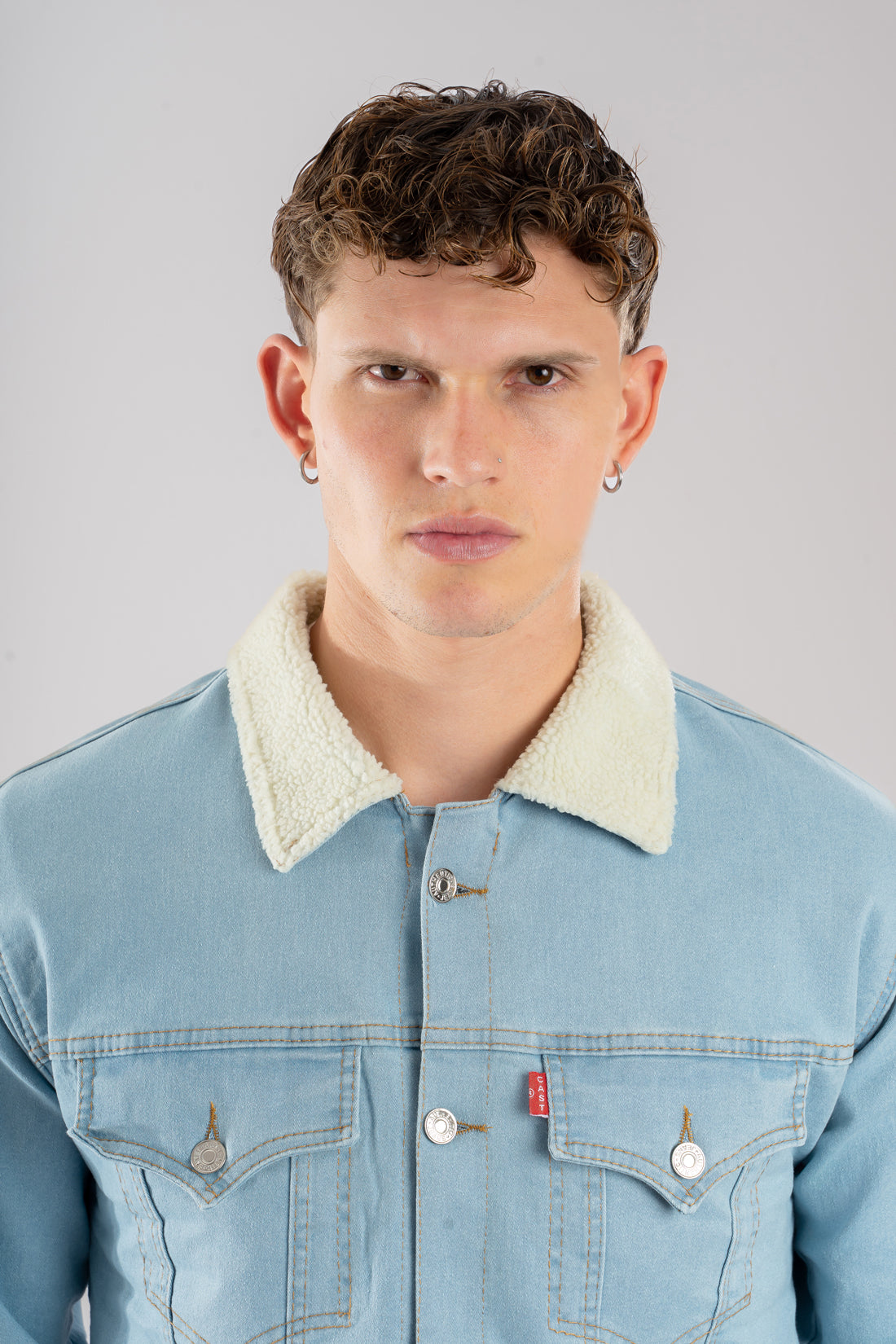 Primer plano de la textura del frente y el cuello de una chaqueta de jean ovejero azul hielo de hombre.