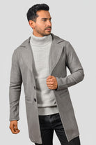 Hombre vistiendo un gabán largo y minimalista modelo Oriente en color gris claro, mostrando un look moderno.