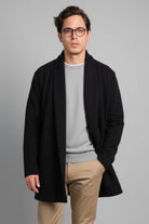 Hombre vistiendo el Gabán Raba en color negro, destacando su diseño abierto con solapa ancha y confección en paño cachemir.