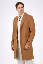 Hombre vistiendo el Gabán Saga tabaco de LSJ SAS, confeccionado en paño licrado premium con corte elegante de 96 cm de largo.